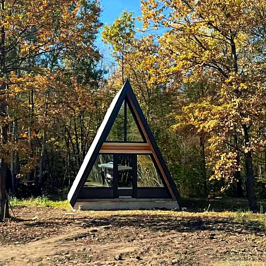 A-frame vikendica u šumi sa trouglastim zastakljenjem